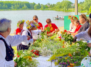 Na zdjęciu osoby robią wianki z roślin nad zalewem w Ozorkowie.