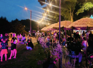 Na zdjęciu osoby bawią się wieczorem na plaży nad zalewem w Ozorkowie.